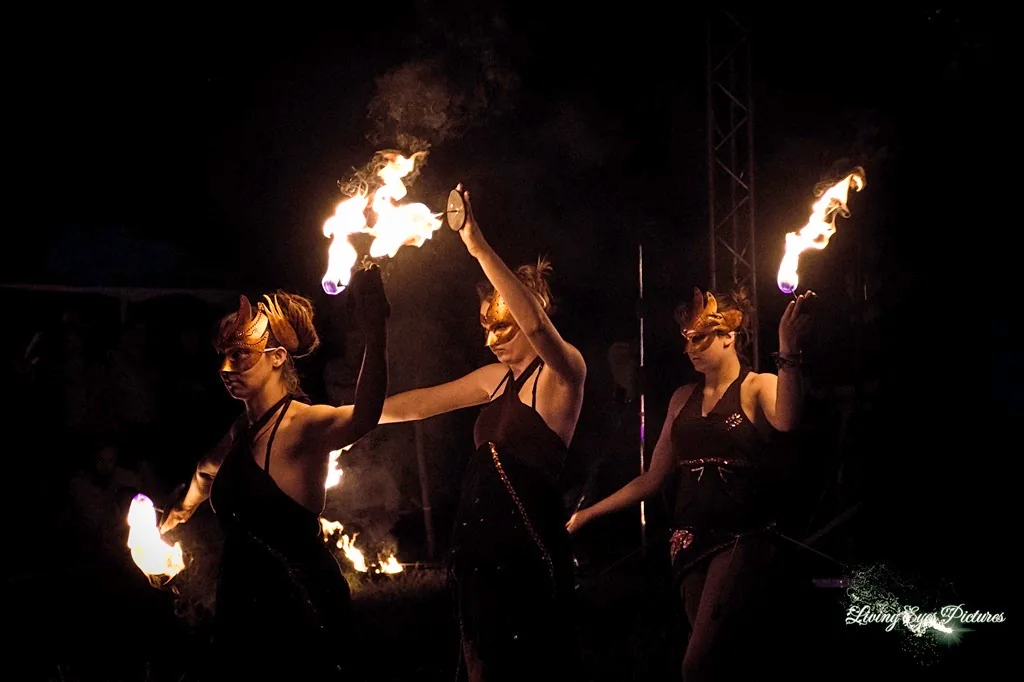 Drei Tänzerinnen mit goldenen Masken und brennenden Handfackeln bei einer Feuershow in Lemgo.
