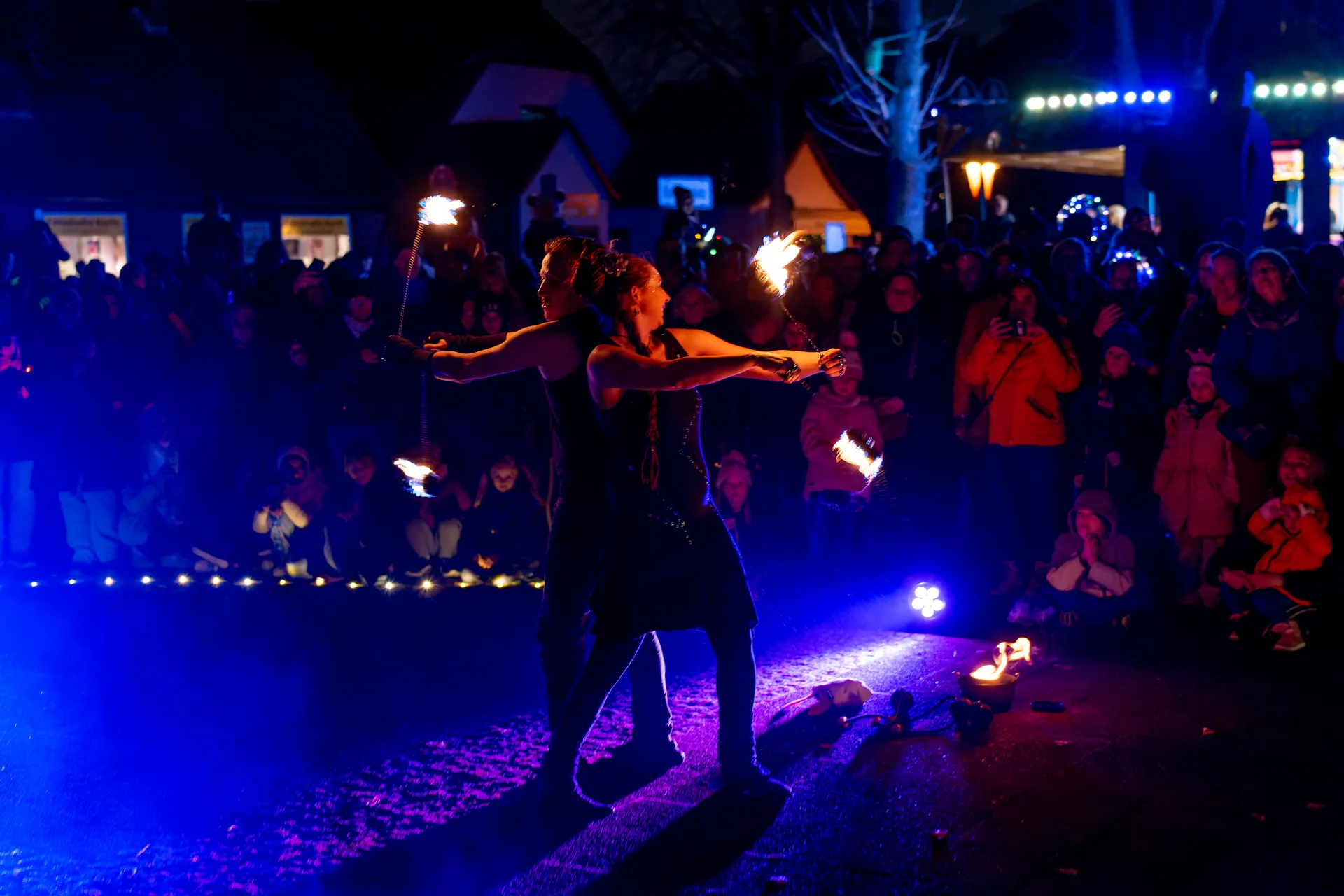 Feuershow-Duo zeigt Partnerpoi-Performance vor Publikum auf einem Stadtfest in Hameln.