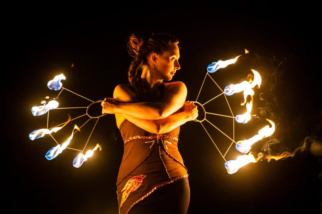 Künstlerin von Elements of Fire posiert fokussiert mit zwei großen brennenden Feuerfächern.