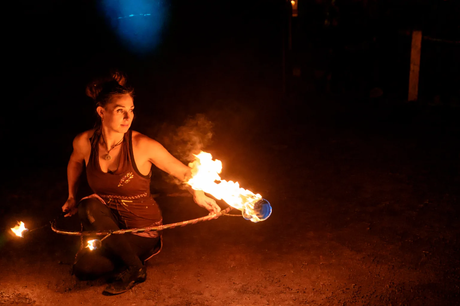 Feuerkünstlerin von Elements of Fire zeigt einen ausdrucksstarken Feuertanz mit einem brennenden Hula-Hoop-Reifen bei Nacht.