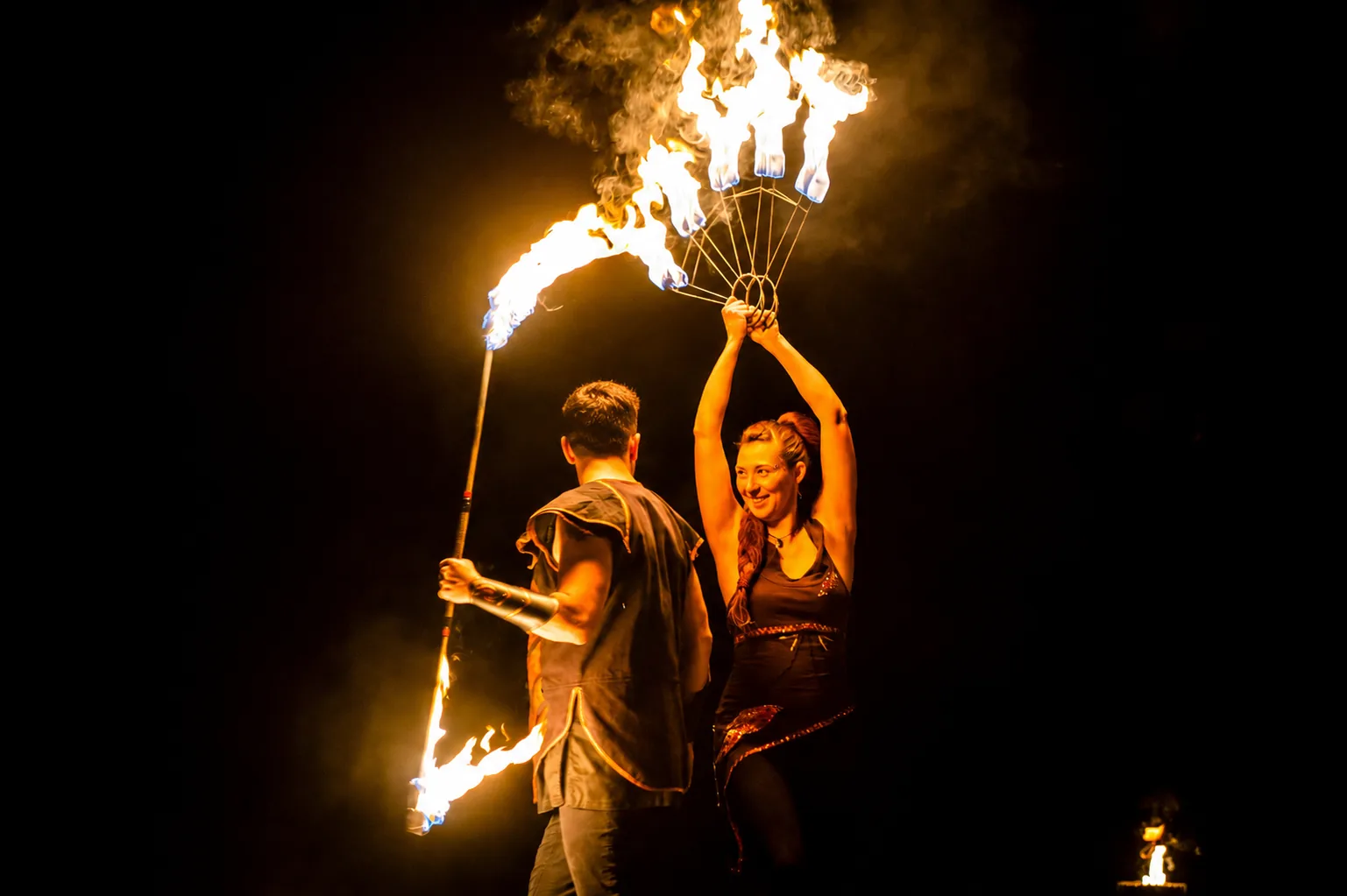 Professionelles Feuerkünstler-Duo von Elements of Fire bei einer packenden Feuerjonglage mit brennendem Staff und Feuerfächern.