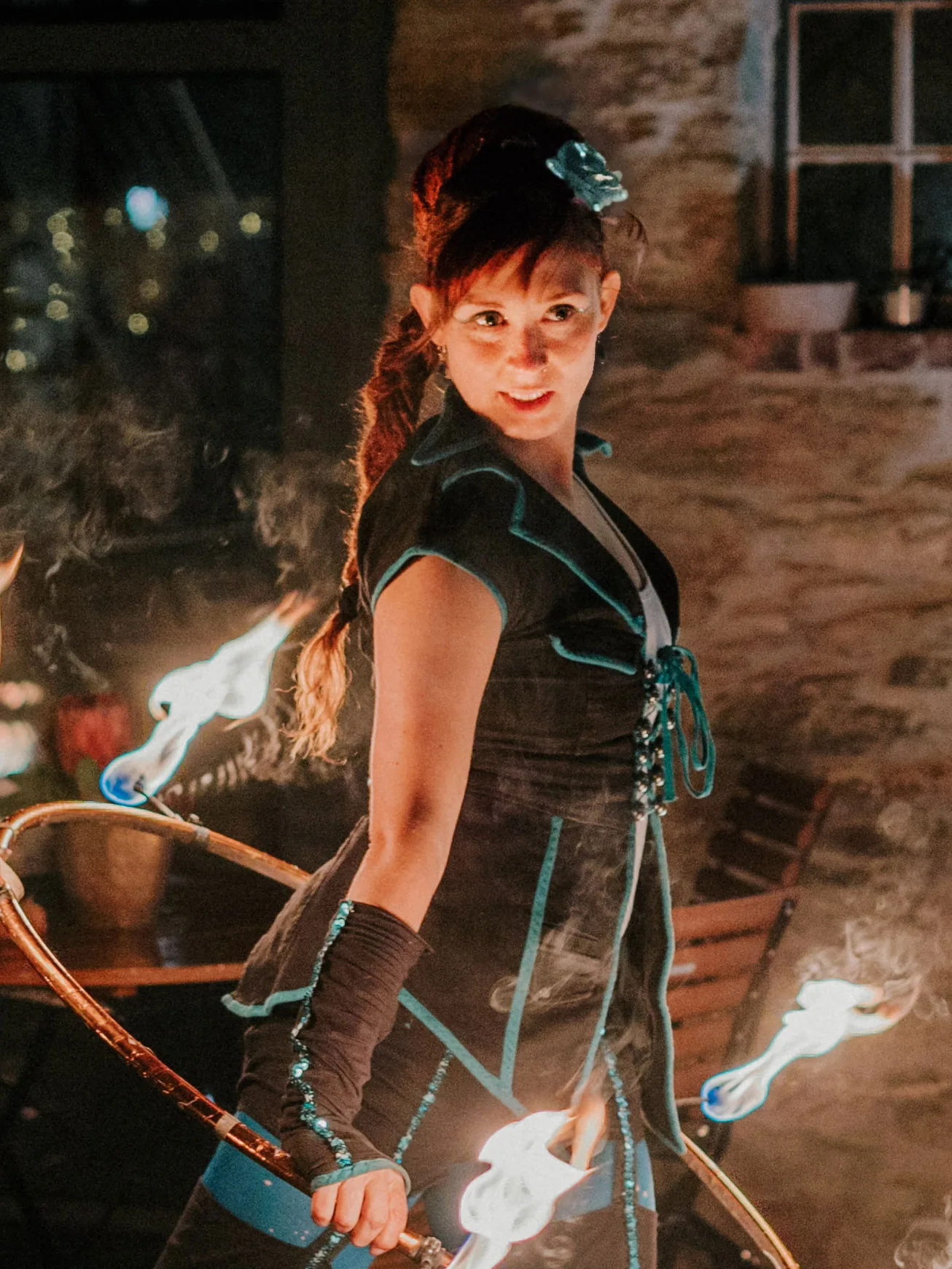 Portrait der Feuerkünstlerin Fenja von Elements of Fire während einer Feuershow mit einem brennenden Hula-Hoop-Reifen.