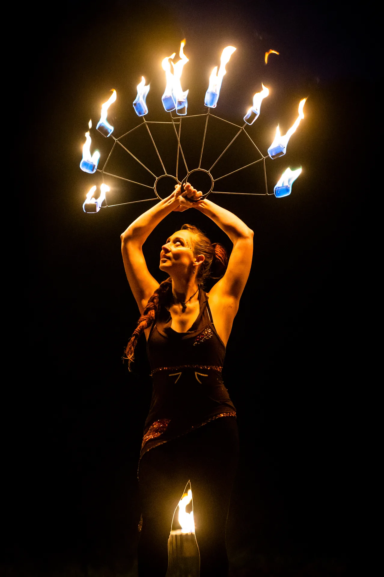 Professionelle Solokünstlerin von Elements of Fire mit zwei brennenden Feuerfächern bei einer Feuershow in Hannover.
