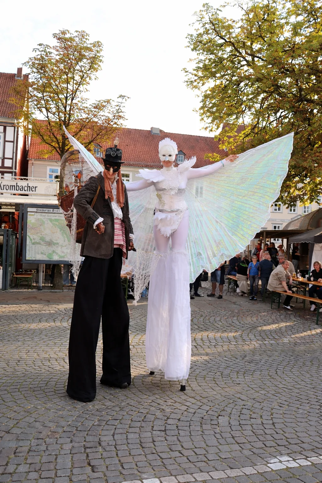 Stelzenläufer-Duo als Vogelfänger und weißer Paradiesvogel auf einem Marktplatz in Gelsenkirchen.