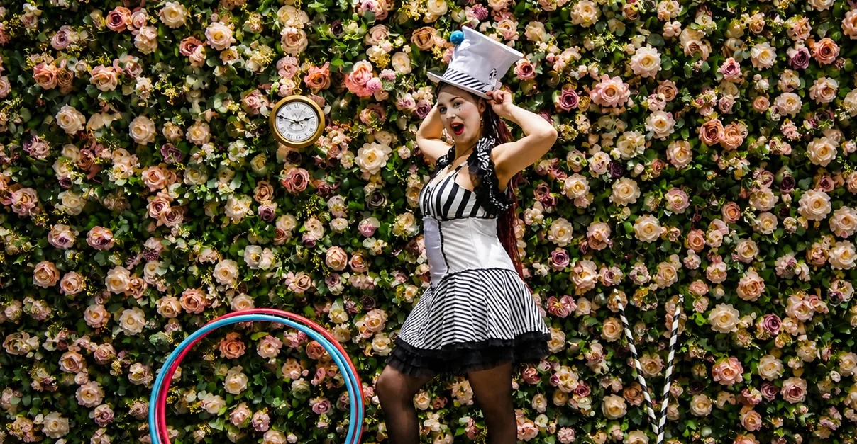 Varieté-Künstlerin posiert mit Hula-Hoop-Reifen vor einer prachtvollen Rosenwand in Hameln.