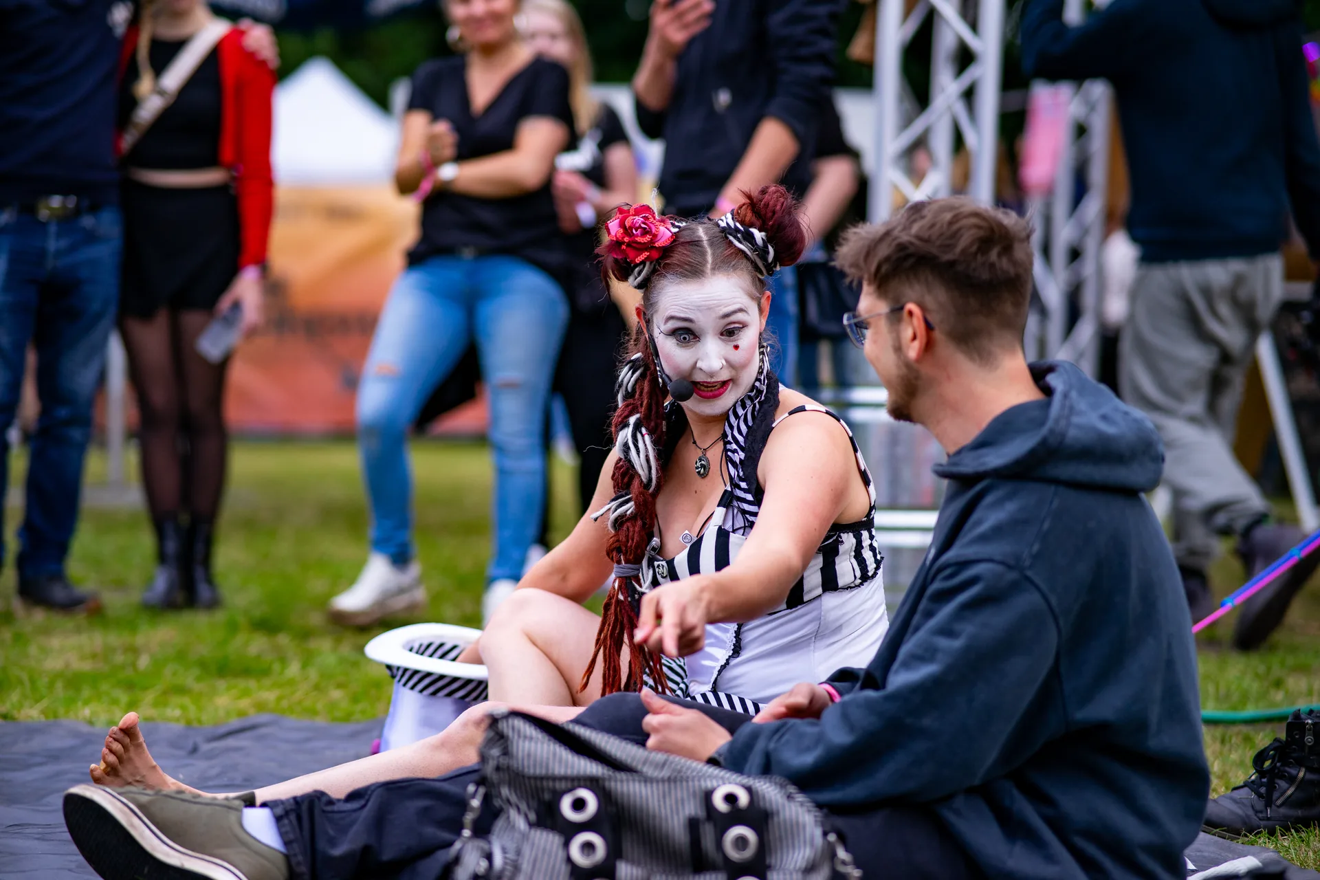 Interaktive Eventunterhaltung in Gütersloh mit einer Circus-Künstlerin, die mit einem Besucher im Gras sitzt.